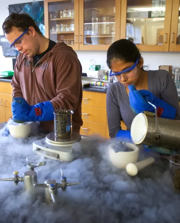 Two students working in a classroom lab create dry ice